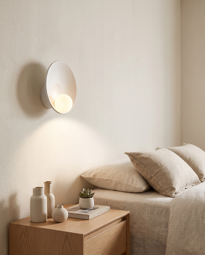 Luna Round Wall Sconce in White above a bedroom nightstand