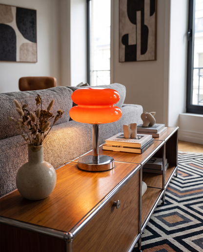 Tarta Table Lamp in Orange Red on a living room console beside a sofa
