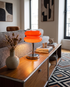 Tarta Table Lamp in Orange Red on a living room console beside a sofa