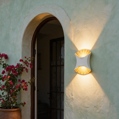 Solene white and gold wall light beside a Mediterranean arched doorway at evening