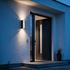 Strato linear up down wall light beside a contemporary pivot front door at blue hour