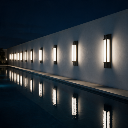 Linnea wall lights along a rendered wall beside a lap pool reflecting at night