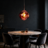 Drift Melt Glass Globe Pendant Light in Wine Red above a marble dining table in a dramatic dining room