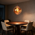 Drift Melt Glass Globe Pendant Light in Gold above a round walnut dining table in a warm dining room