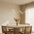 Yardley zigzag wave pendant light in gold above a round travertine dining table