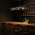 Verona peak linear pendant light in black over a walnut bar counter