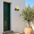 Solar sunrise outdoor wall light on a white rendered facade beside a green front door in sunshine