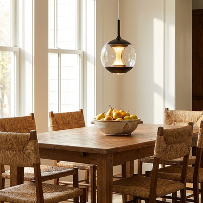 Orsini clear glass orb pendant light hanging above a dining room table with rush chairs