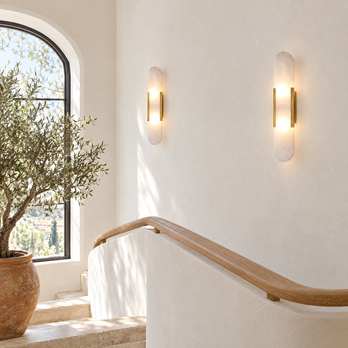 Alba Alabaster Wall Sconce in Brass on a white plaster staircase landing in a Mediterranean home