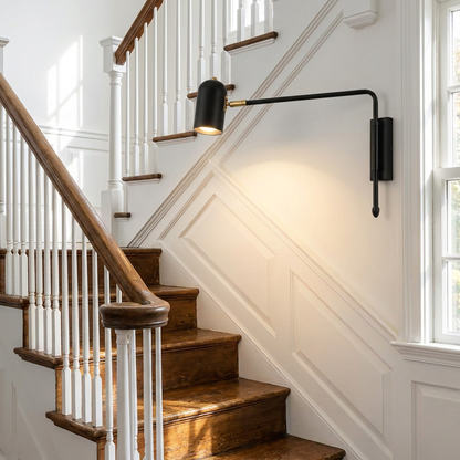Arley hardwired swing arm reading wall lamp in black and gold on a staircase wall