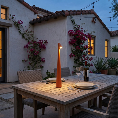 Amaryn cordless cone table lamp in Orange on a patio dining table