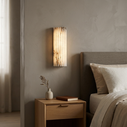 Vianney Ribbed Alabaster LED Wall Sconce beside a bed